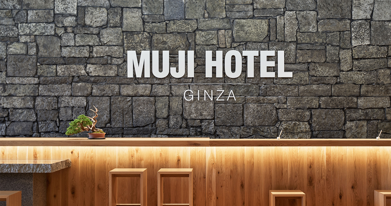 MUJI HOTEL GINZA — 東京・銀座 · 石積みの壁とフロントが据えられた共用部
