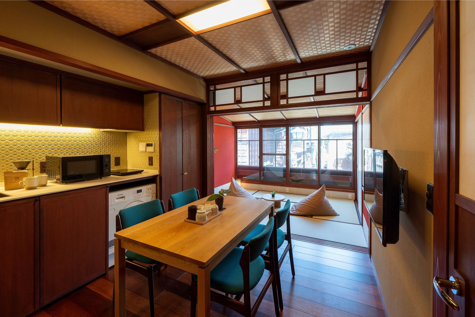 謡町 UTAIMACHI — 金沢市東山 · 朱壁の和室とキッチンを備えたダイニング、ひがし茶屋街に面した客室内観