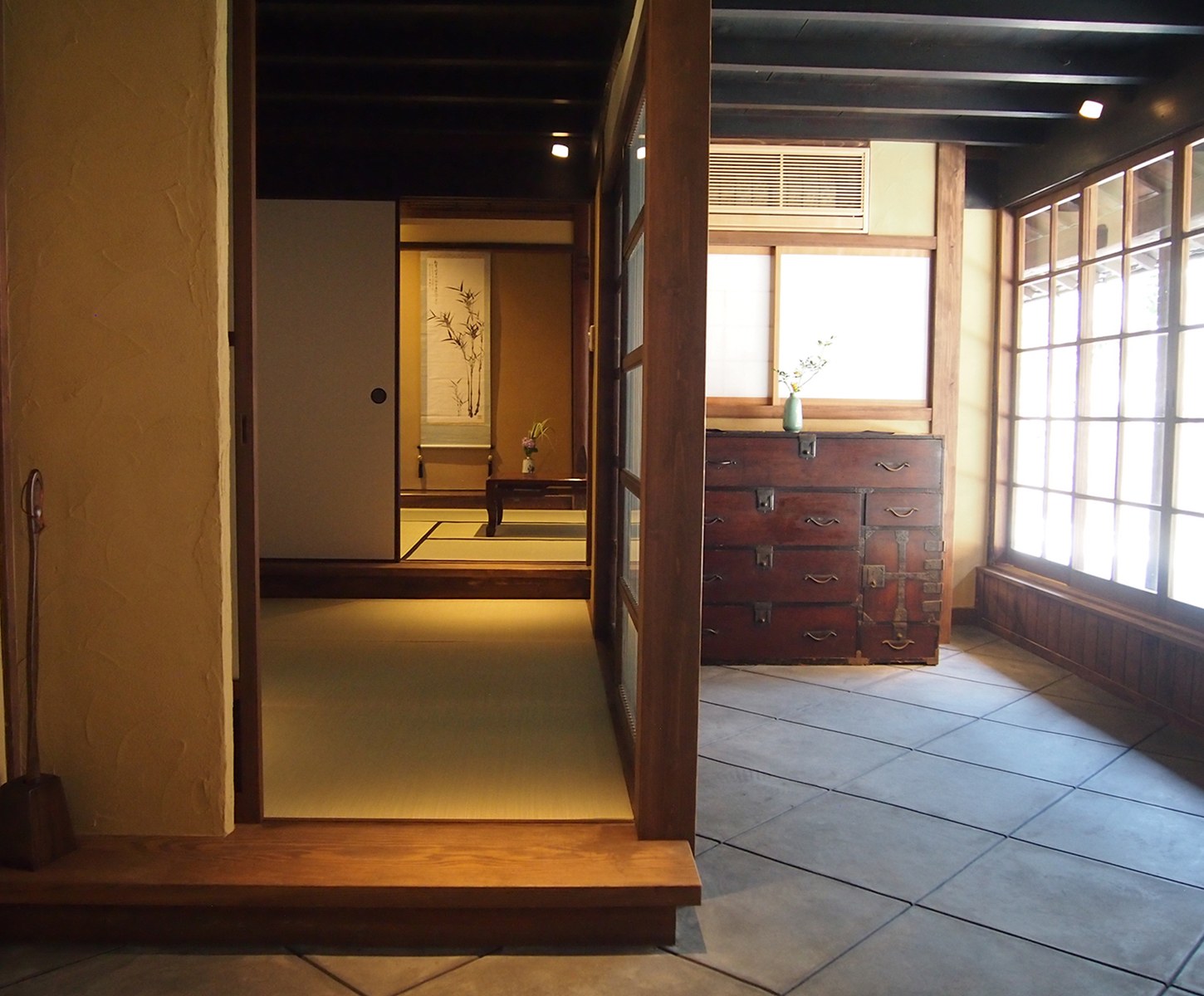 町家ステイ吹屋 千枚の内部 — 土壁と框、明治初期の和箪笥を据えた玄関から座敷を見通す