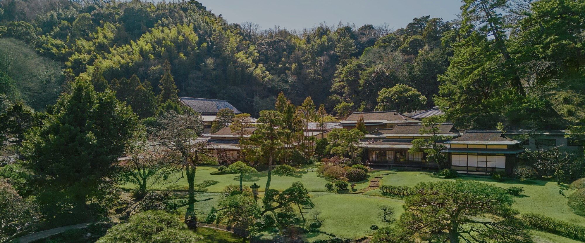 三養荘 — 静岡県伊豆の国市・源氏山の山懐に、平屋の数寄屋が3,000坪の池泉回遊式庭園へ分棟で伏せる全景