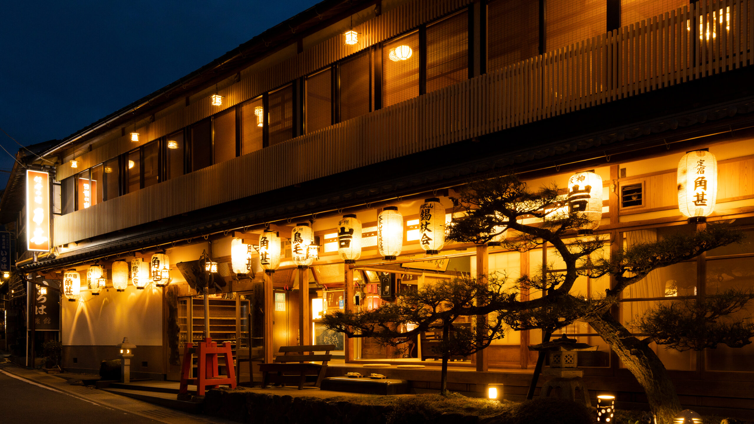 角甚 — 天川村洞川 · 講の名を記した提灯が連なる夜の木造館外観