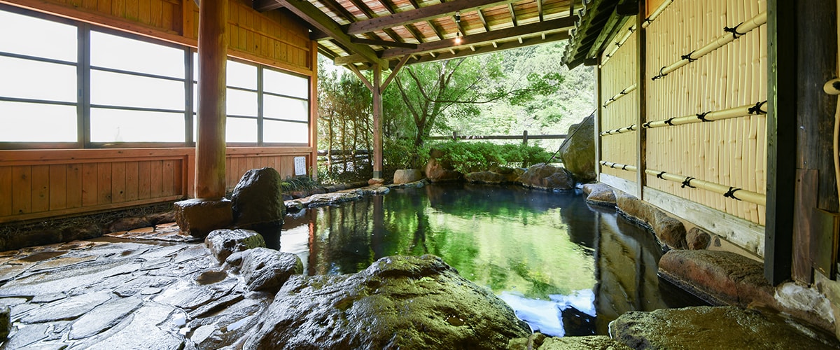 筋湯温泉 旅館白滝 — 大分県九重町湯坪 · 竹を編んだ袖壁と杉板の軒下に据えられた岩組みの露天風呂