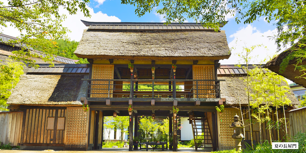 悠湯里庵 — 群馬・川場温泉 · 夏空に映える茅葺きの長屋門と青萱の稜線