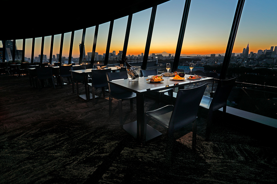 VIEW & DINING THE SKY — ザ・メイン17階、弧状の窓面と日没時の都心パノラマ