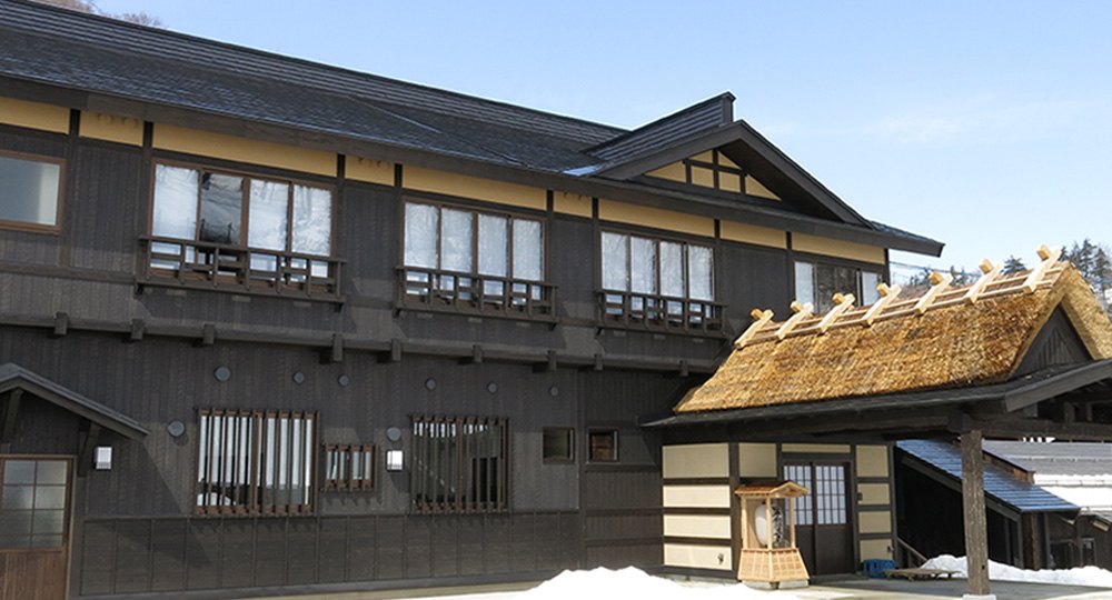 泥湯温泉 奥山旅館 — 秋田県湯沢市 · 2019年に再建した黒壁の本館と、茅を葺いた玄関まわり