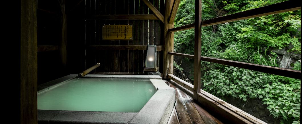 深山荘 高見屋 — 山形・蔵王温泉 · 蔵王石で刳った露天石風呂と竹の湯口、板張りの湯屋