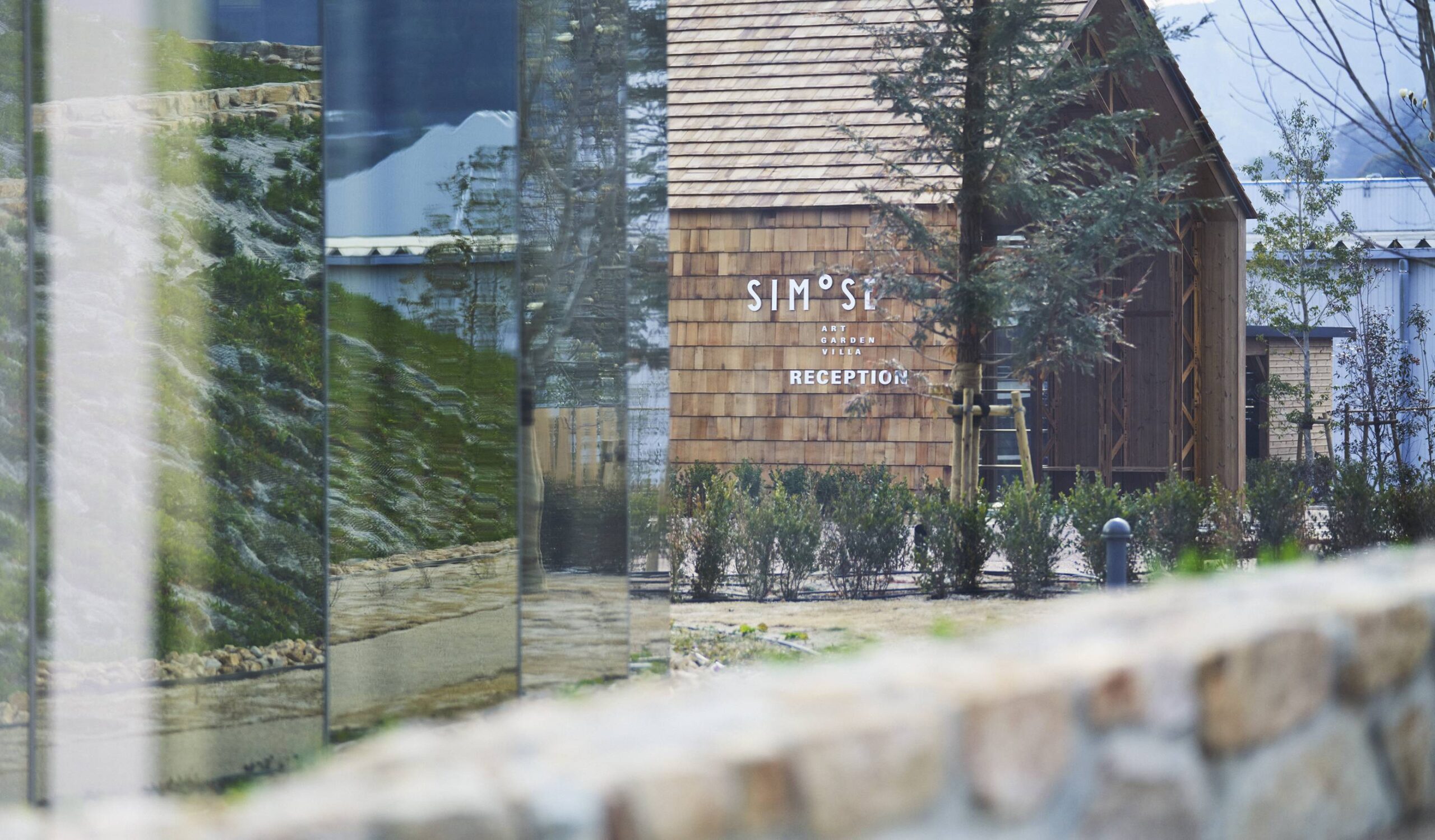 SIMOSE ART GARDEN VILLA レセプション棟 — 広島県大竹市 · ミラーガラス越しに見る杉材の切妻屋根