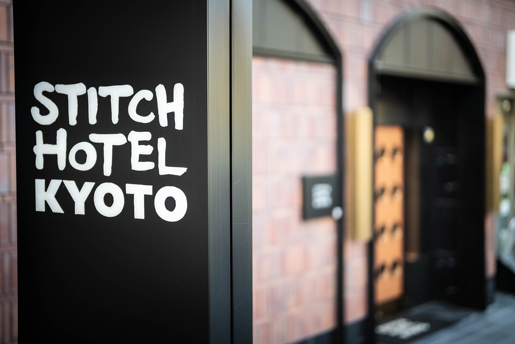 STITCH HOTEL Kyoto — 京都市下京区西石垣通 · 煉瓦とアーチ開口で構成された路地側のエントランス