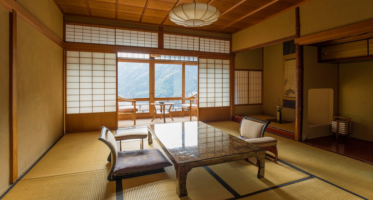 湯之島館 — 下呂市湯之島 · 本館特別室の数寄屋座敷、広縁のガラス戸越しに下呂の町と飛騨の山並み