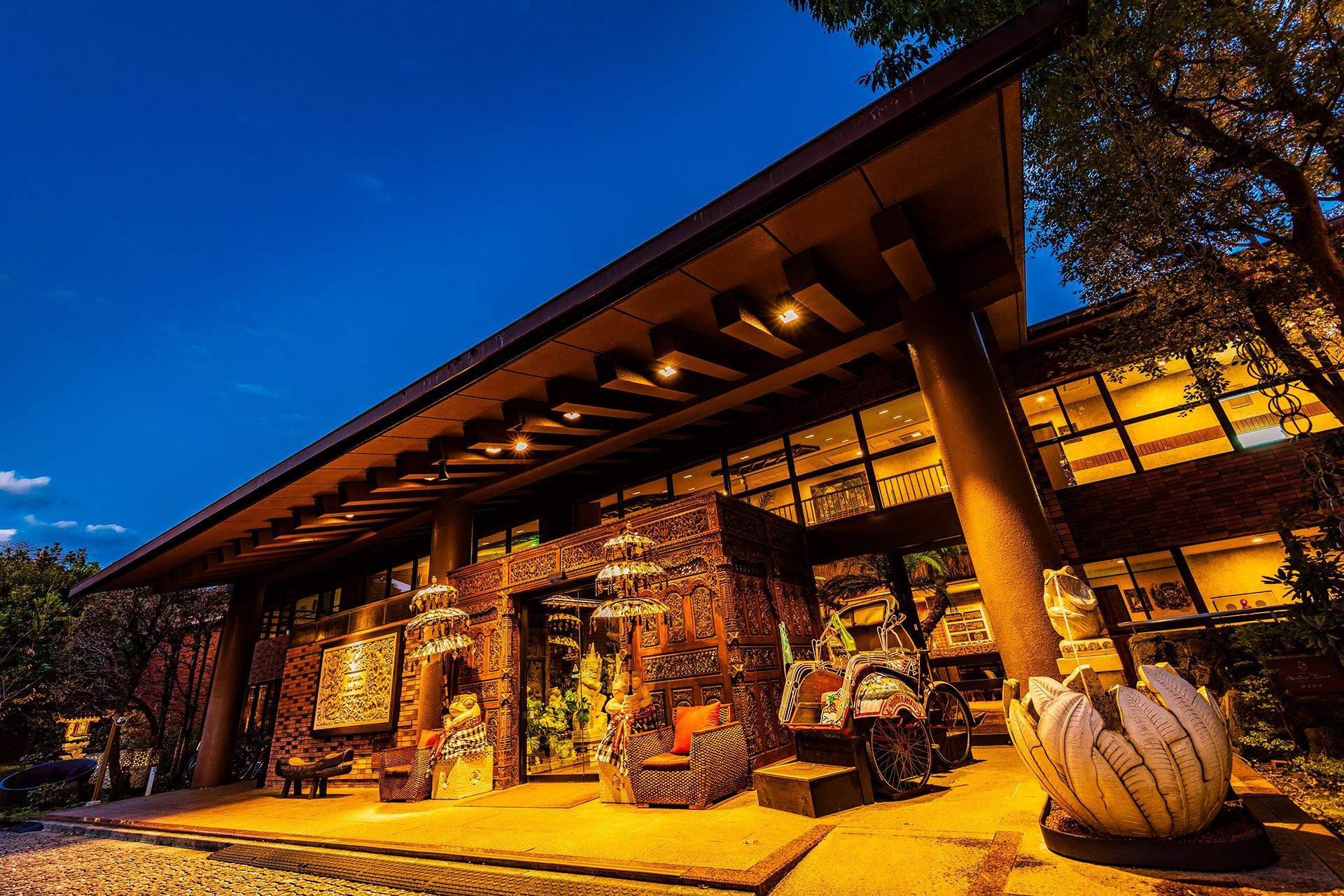 ホテル&スパ アンダリゾート伊豆高原 — 伊東市八幡野 · バリの彫刻扉と大屋根のエントランス夜景