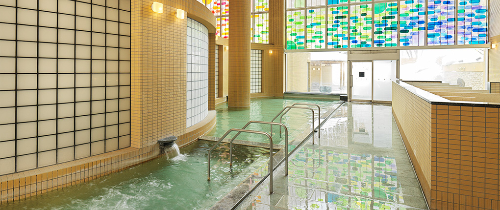 定山渓 鶴雅リゾートスパ 森の謌 — 札幌・定山渓温泉 · 高い天井とステンドグラスの窓から光が入る大浴場