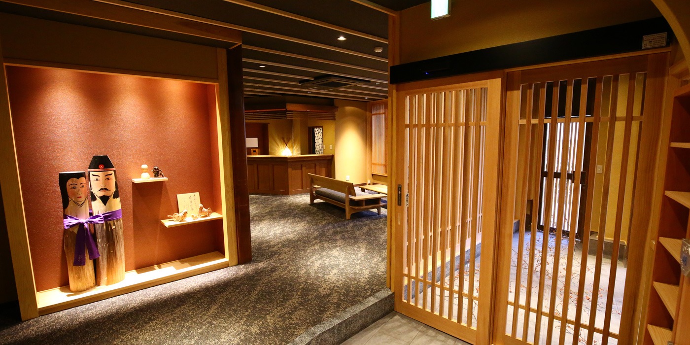 中島屋旅館 — 野沢温泉・熊の手洗湯前 · 格子戸と飾り棚、間接照明で整えた館内の廊下
