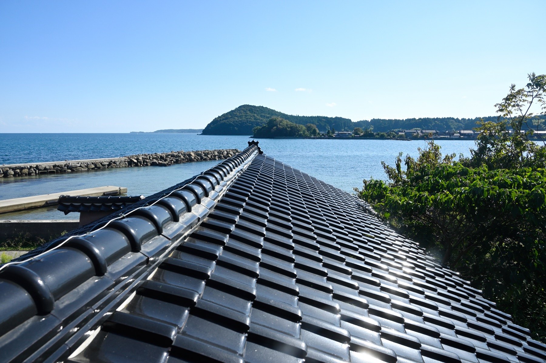 能登KNOT, LABO & Gallery — 穴水町甲 · 黒い瓦屋根越しに見る穴水の湾と対岸の島影