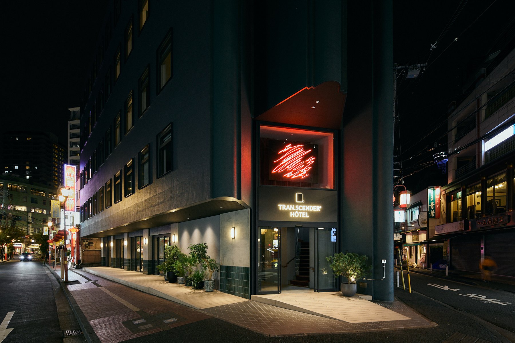 TRAN.SCENDER HÔTEL Yokohama — 横浜中華街・山下町 · 飲食店ビルを転用した地上6階のホテル、夜の外観とネオン